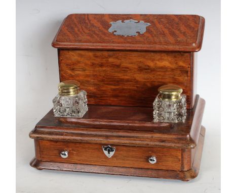 An early 20th century oak desk top standish,  lidded letter rack back, twin inkwell pen tray, base drawer, 26cm high, 31.5cm 