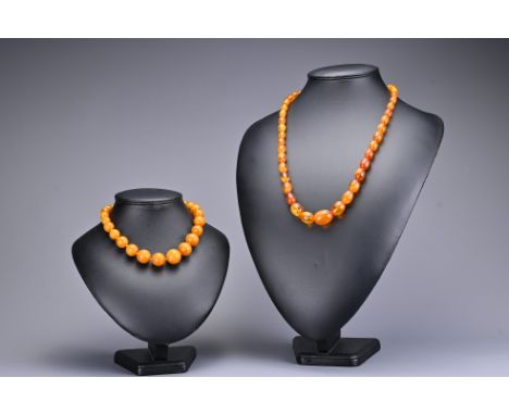 An amber coloured graduated spherical bead necklace with screw clasp together with a graduated amber bead necklace with metal