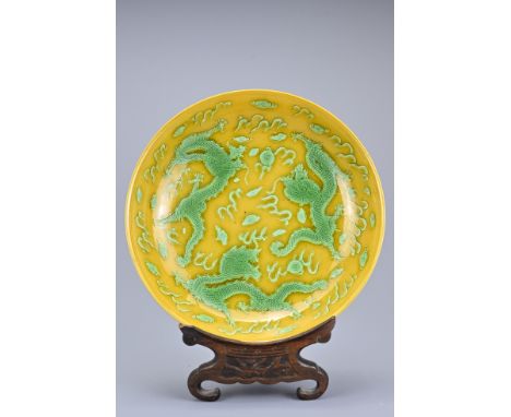 A Chinese yellow and green glazed porcelain dragon dish. The dish decorated with three dragons chasing flaming pearls amongst