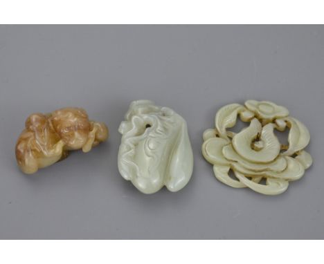 Three Chinese jade pendants to include a mottled brown and celadon jade carving of lion dog with branch in its mouth. Melon g