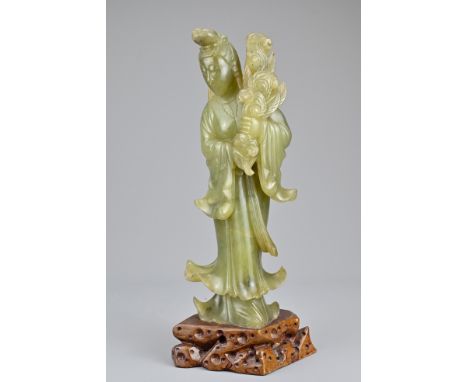 A Chinese early 20th Century carved jade figure of Guanyin mounted on soapstone stand. 29cm tallOverall good condition withou