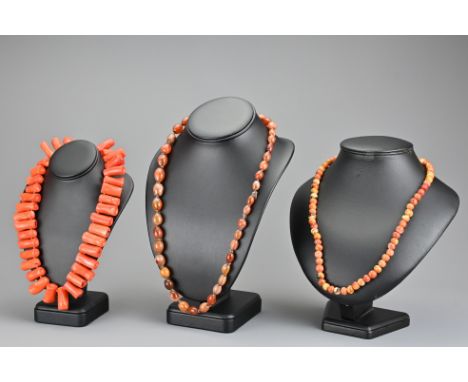 A bamboo coral necklace with metal spring ring clasp, a string of graduated agate beads and one other beaded necklace. Bamboo