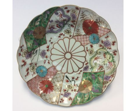 A Worcester deep plate, brocade pattern with a lobed rim, painted in the Japanese taste with panels of dragons, prunus flower