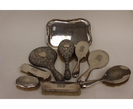 A matched Edwardian silver dressing table set including shaped oblong tray; four brushes, mirror, all engraved with monogram,