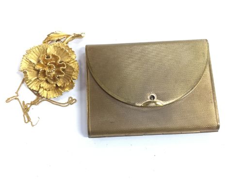 A yellow metal brooch in the form of a flower, stamped A85, with a yellow metal engine turned powder compact (2)