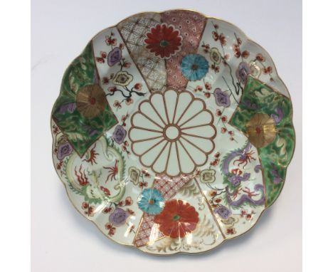 A Worcester deep plate, brocade pattern with a lobed rim, painted in the Japanese taste with panels of dragons, prunus flower