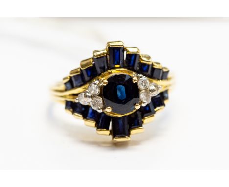  An 18ct. gold, diamond and sapphire dress ring, having navette form head set central round brilliant cut sapphire flanked by