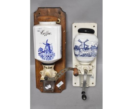 Two vintage wall mounted coffee grinders having blue and white scenes to ceramic containers and glass receptacles for holding