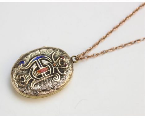 A Victorian yellow metal and enamel locket pendant, of oval form with embossed and engraved decoration, enamelled monogrammed