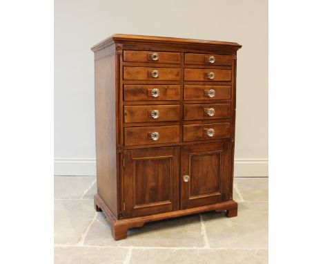 An early 20th century walnut specimen cabinet, the rectangular moulded top above an arrangement of ten graduated drawers appl