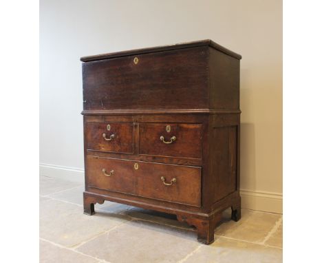 An 18th century and later oak coffer on chest, the rectangular hinged cover enclosing a candle box raised upon an associated 