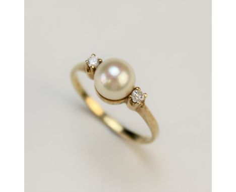 A pearl and diamond three stone ring, the central cultured pearl measuring approx. 7mm, flanked by a round brilliant cut diam