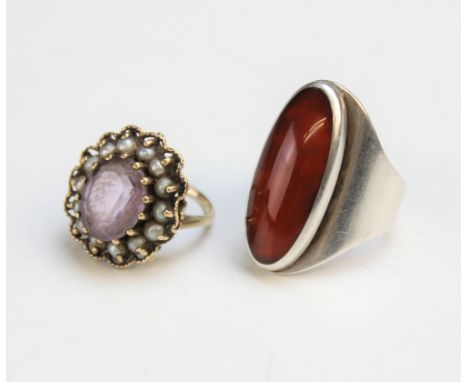 An amethyst and simulated pearl set dress ring, the central oval amethyst (measuring 12mm x 10mm), with a surround of fourtee