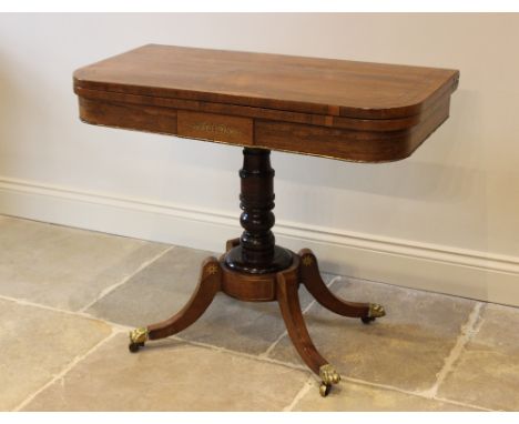 A George IV brass inlaid rosewood pedestal card table, the folding top inlaid with a frieze of brass flowerhead motifs within