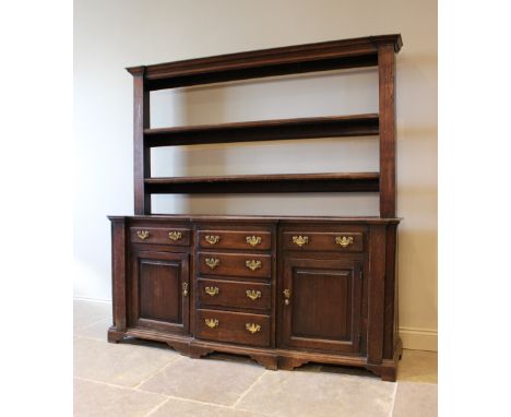 A George III oak North Walian breakfront dresser, the open plate rack with a moulded cornice above two shelves, upon the base