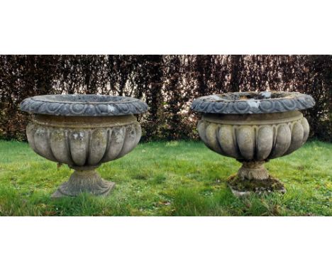 Three reconstituted stone garden urns/planters, of circular form with gadrooned decoration, with two associated stands (5) Fo