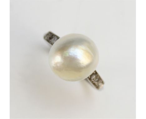 An Art Deco pearl and diamond ring, the central untested Baroque pearl (measuring approx 11mm diameter) flanked by rose cut d