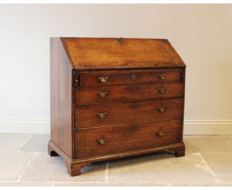 A George III oak bureau, the fall front enclosing a compartmentalised interior with small drawers and pigeon holes flanked by