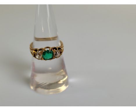 An 18ct gold emerald and diamond three stone dress ring, the circular mixed cut emeralds in claw setting flanked by two old c