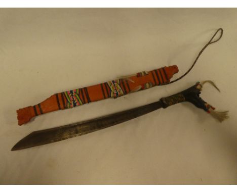 A Borneo Dyak tribal sword in painted carved hilt and scabbard