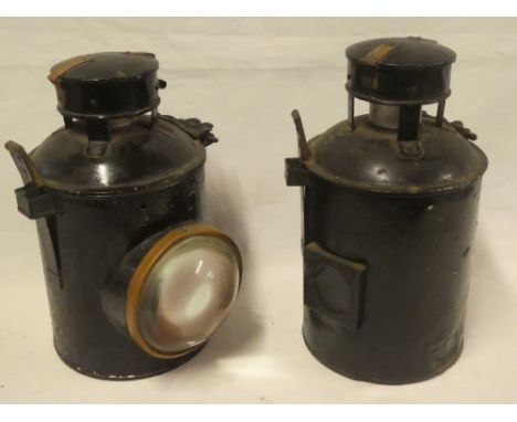 Two painted metal copper mounted cylindrical railway lamps, one with bulls-eye glass lens and both with internal oil lamp fit