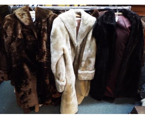 Three fur coats, one in black approximate length 115 cm, one in white approximate length 115 cm and a further coat with label
