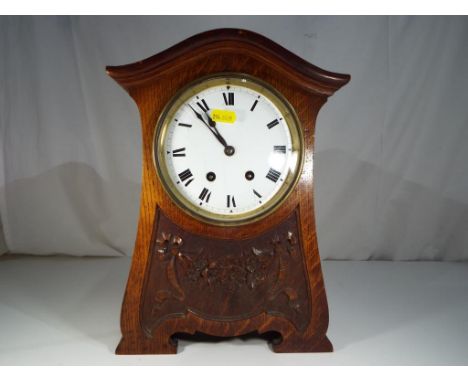 A good Art Nouveau oak cased mantel clock, the case having incised and carved decoration, opening glazed bezel to access the 