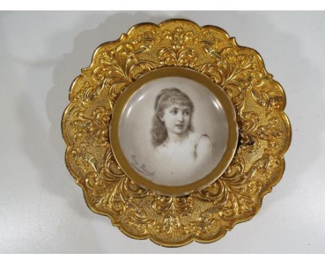 A brass framed signed ceramic plaque. Estimate £25 - £35