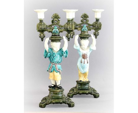 A Pair of Majolica Figural Twin-Light Candelabra, circa 1870, in the Chinoiserie style formed as a young girl and boy, glazed