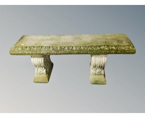 A weathered concrete garden bench on classical style supports, width 118 cm 