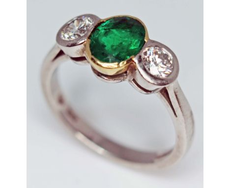 A diamond and emerald ring, the oval cut emerald measuring approx. 7.85mm x 6.10mm x 3.75mm, approx. wt. 1 carat, two round b