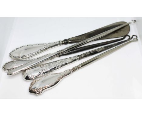 Four hallmarked silver handled button hooks and a hallmarked silver handled shoe horn.  