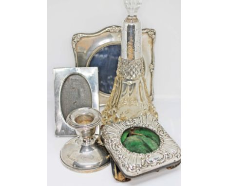 A mixed lot of hallmarked silver comprising two photo frames, a clock frame and a candlestick, together with a white metal co