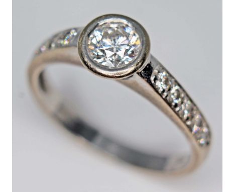 An 18ct gold diamond ring, the bezel set round brilliant cut central stone approx. 0.56 carats, diamond set shoulders, hallma