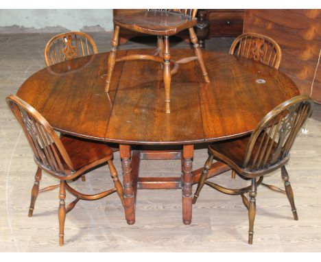 An aged oak gate leg table and six crinoline chairs in the manner of Titchmarsh and Goodwin.