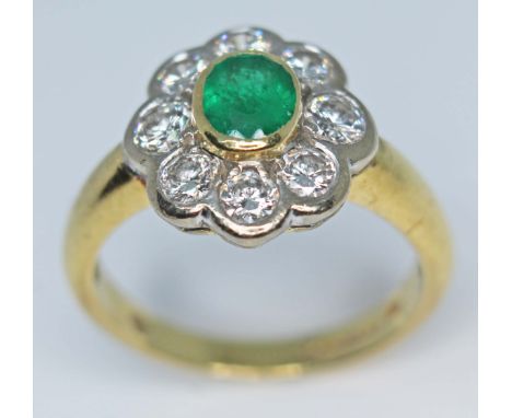 A diamond and emerald oval cluster ring, the central oval cut emerald measuring approx. 6mm x 5mm x 3mm, wt. approx. 1 carats