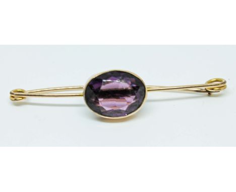 A yellow metal mounted brooch set with an amethyst coloured stone, length 6cm, gross wt. 5.2g.  