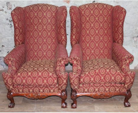 A pair of reproduction Georgian style armchairs with wing back, scroll arms, carved cabriole legs and red and gold patterned 