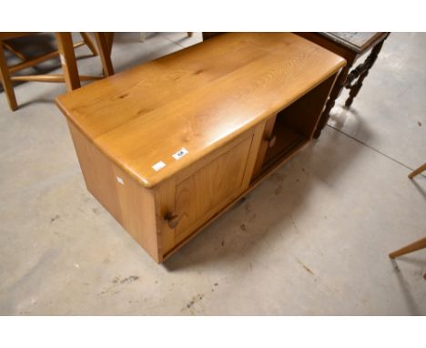 A light Ercol TV unit having sliding doors and castors, width approx. 89cm