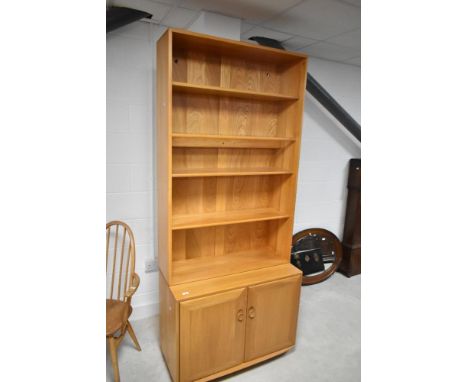 A light Ercol bookcase having double cupboard under, approx dimensions H214cm W91cm D44cm
Condition report: In good original 