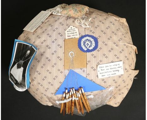 A Honiton bobbin pillow and assorted bobbins, circa 1900, with note attached stating it was used in the nearby village of Bee