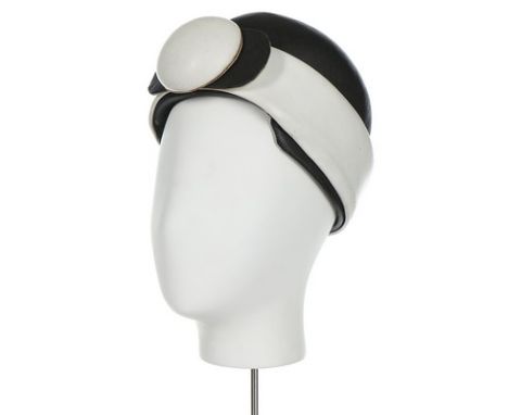 A Christian Dior futuristic hat, mid 1960s, labelled 'Licence Chapeuaux', with wide leatherette band and medallion to front  