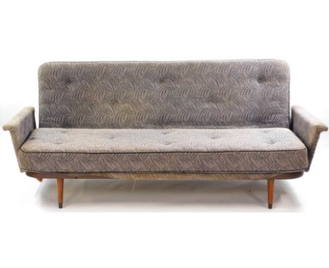 A mid century sofa come day bed, with a sprung metal frame, upholstered in stylised leaf patterned fabric, raised on teak tur
