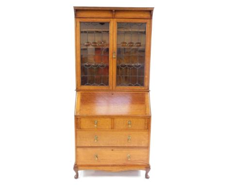 A Victorian Arts &amp; Crafts style light oak bureau bookcase, the beaded pediment above a pair of glazed doors enclosing thr