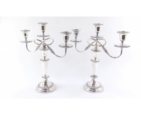 A pair of three branch silver plated candelabra, with detachable upper sections and nozzles, raised on circular bases, 40cm H