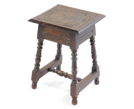 A Victorian stool come occasional table, the square hinged top carved with a portrait of an elderly lady in a leaf and berry 