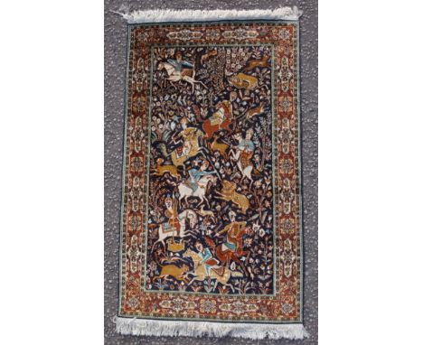 Persian silk rug depicting a hunting scene, the noire field with figures on horseback with hounds hunting a lion and deer, wi