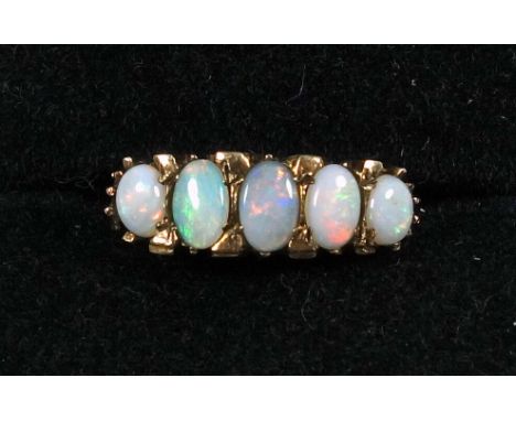 A yellow metal five stone graduated opal ring in a scroll pierced gallery mount on a metal loop stamped 9ct, ring size K 1/2,