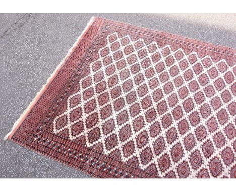 Pakistani Bokhara carpet, the ivory field with all-over Salor type guls, within a terracotta geometric rosette border and mul