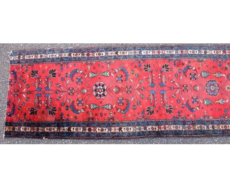 Persian runner, the madder field with all-over floral decoration, within ivory and indigo rosette borders and zig-zag guards,